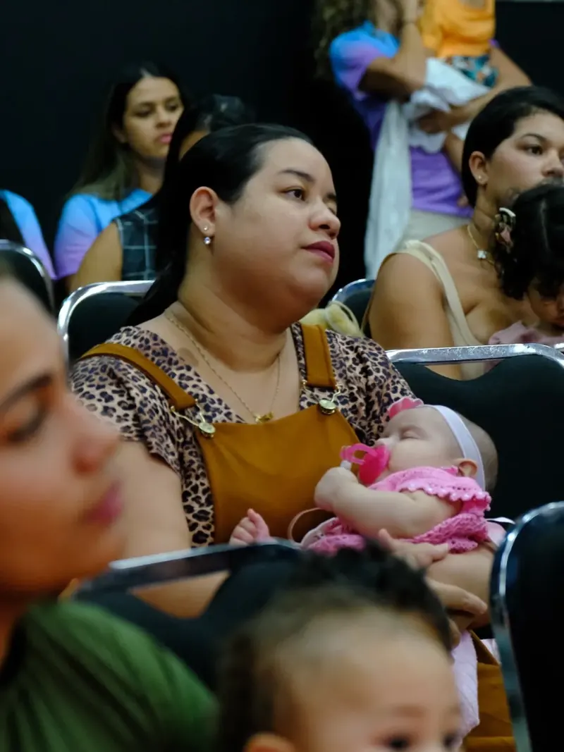 Mãe com bebê no colo durante atividade da Secretaria